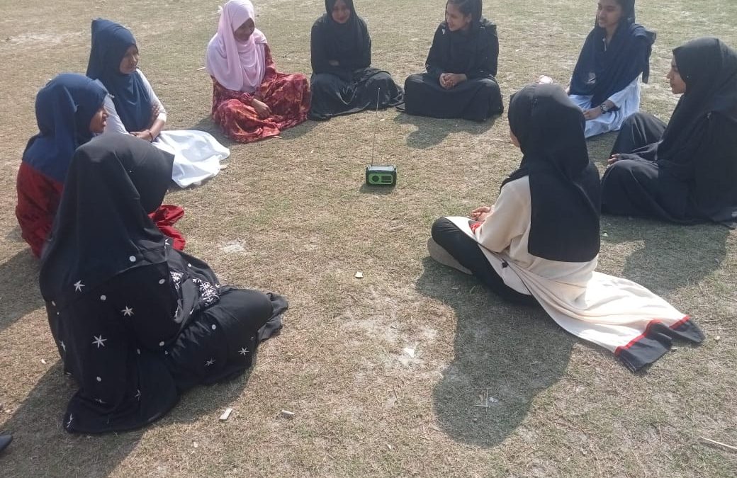 খোলা মাঠে রোদে বসে রেডিও মেঘনা শুনছেন পদ্ম ক্লাবের সদস্যরা